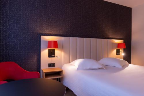 a bedroom with a white bed and a red chair at L'Amirauté Brest in Brest