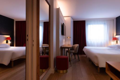 a hotel room with two beds and a mirror at L'Amirauté Brest in Brest