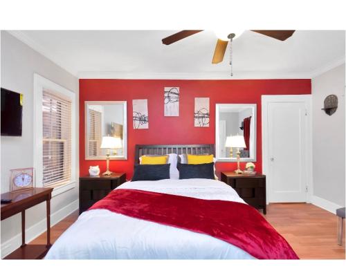 a bedroom with a red wall with a bed and two tables at Cozy Downtown Studio by Toyota Center in Houston