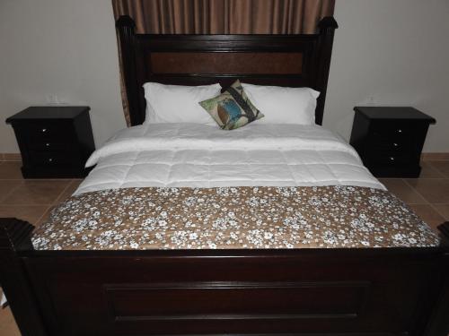 a large bed with a wooden headboard and two night stands at Amro Petra Apartment in Wadi Musa