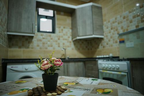 a kitchen with a table with a vase with flowers on it at Amro Petra Apartment in Wadi Musa