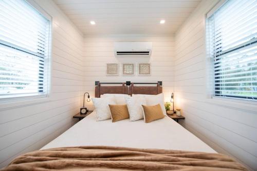 a bedroom with a large bed with white walls at The Newtonian Tiny Container Home near Magnolia in Bellmead