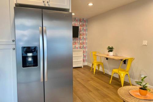 a kitchen with a refrigerator and a table with yellow chairs at Steps To The Beach, Pacific City and Main Street - #2 in Huntington Beach