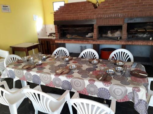 einen Esstisch mit weißen Stühlen und einer Tischdecke darauf in der Unterkunft Mutualidad de empleados del Club Gimnasia y Esgrima de Buenos Aires in Mar de Ajó