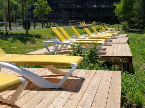 a row of yellow chairs sitting on a wooden deck at Chalet F116 Mont-Tremblant Nord in Lac-Superieur