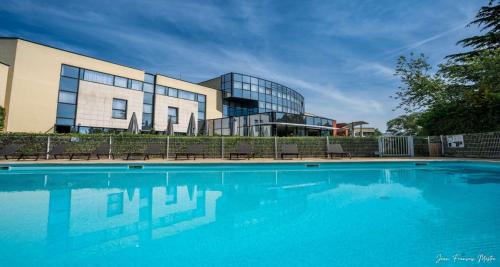 un bâtiment avec une piscine en face d'un bâtiment dans l'établissement Best Western Plus Metz Technopole, à Metz