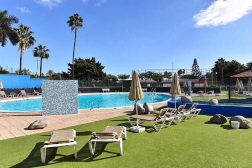 a pool with lounge chairs and umbrellas in front of it at The Perfect Stay Maspalomas in Maspalomas