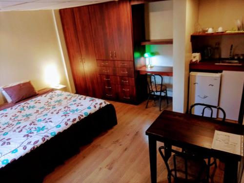 1 dormitorio con cama, mesa y cocina en Casa de Huéspedes Tu Parada en Cuenca, en Cuenca