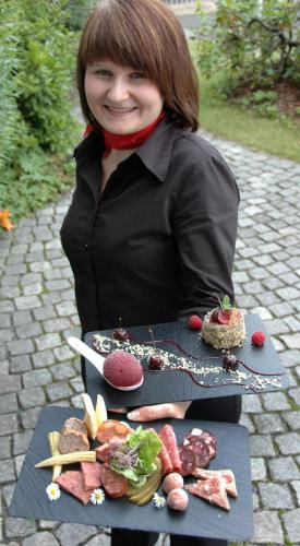 a woman standing in front of a table of food at Hotel Schieferhof - GlasLUST in Neuhaus am Rennweg