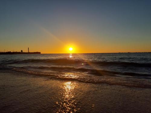 a sunset on a beach with the ocean at Dormir en Cádiz in Cádiz