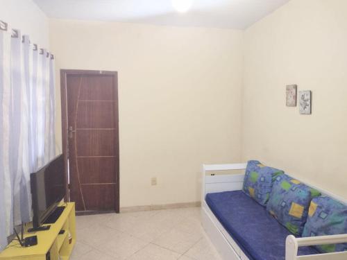 ein Wohnzimmer mit einem blauen Sofa und einem TV in der Unterkunft Casa para temporada em Rio das Ostras in Rio das Ostras