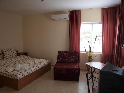 1 dormitorio con 1 cama, 1 silla y 1 ventana en Guest Rooms Kamberovi, en Shabla