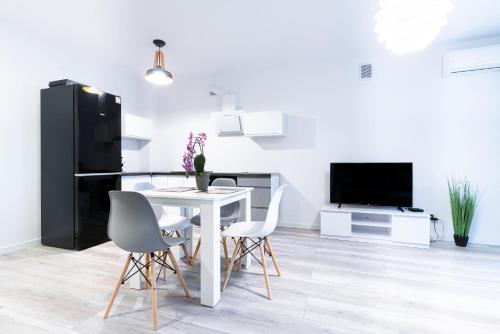 a kitchen with a white table and chairs and a black refrigerator at Apartament Uroczy in Legnica