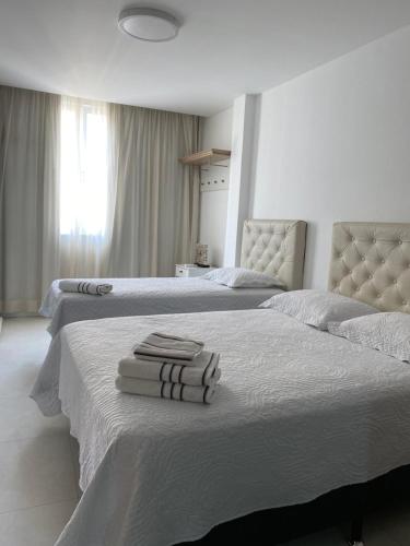 two beds in a bedroom with towels on the bed at Apartamento Copacabana - Quadra da Praia in Rio de Janeiro