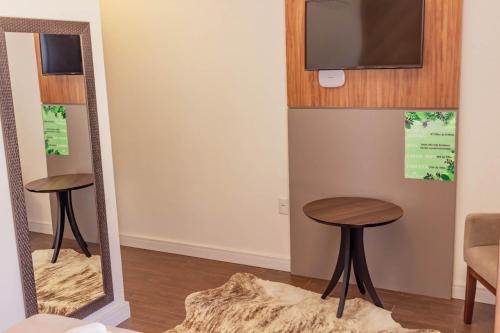 espejo en una habitación con 2 taburetes y TV en Morada do Estaleiro, en Balneário Camboriú