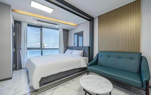 a bedroom with a bed and a couch and a window at Songjeong Blue Castle Hotel in Busan