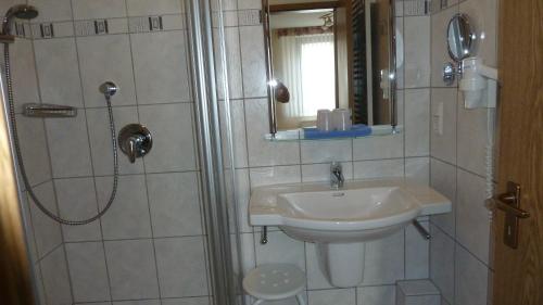 a bathroom with a sink and a shower with a mirror at Ferienhaus am Sonnenhang in Willingen