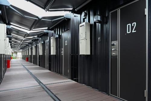 a hallway with black doors and wooden floors at HOTEL R9 The Yard Tsuyama in Tuyama