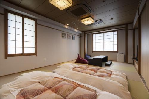 2 camas grandes en una habitación con ventanas en Hotel Ohta, en Ōzu