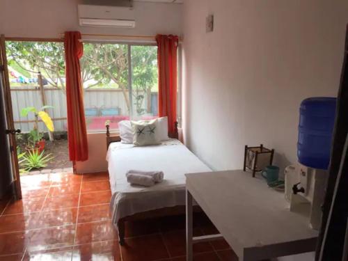 Habitación con 2 camas, mesa y ventana en La Casa de Mike, en Puerto Villamil
