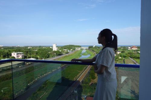 a woman standing on a balcony looking out over a river at Bohemia in Jian