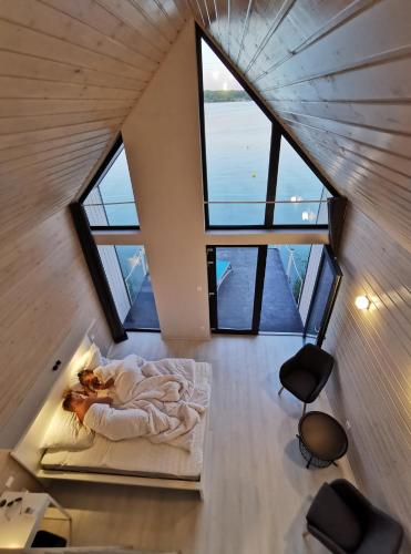 a person laying in a bed in a room with windows at LupaGlamping in Budakalász