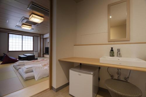 a bathroom with a sink and a bed at Hotel Ohta in Ōzu