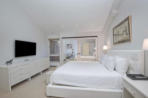 ein weißes Schlafzimmer mit einem Bett und einem Flachbild-TV in der Unterkunft Lionshead Center #304 condo in Vail