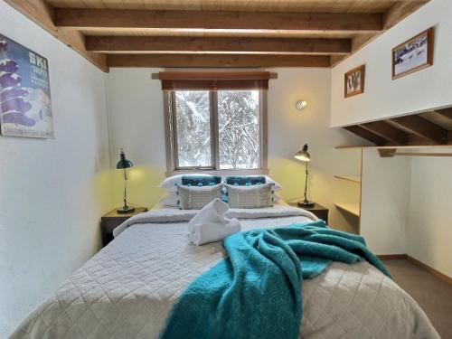 a bedroom with a bed with a blue blanket on it at Merrigang Chalet, Dinner Plain in Dinner Plain
