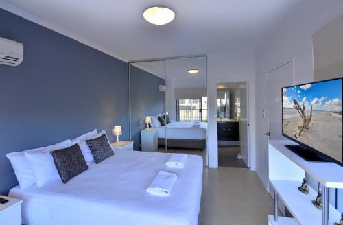 a bedroom with a large white bed and a television at DelMar 3 in Mandurah