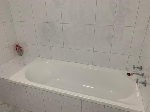 a white bath tub in a white tiled bathroom at Beachside & Jetty View Apartment 6 - Captain's Apt in Streaky Bay