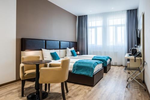 um quarto de hotel com uma cama, uma mesa e cadeiras em RheinCity Hotel & Boardinghouse em Ludwigshafen am Rhein