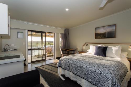 a bedroom with a bed and a kitchen with a sink at Haast Beach Motel in Haast