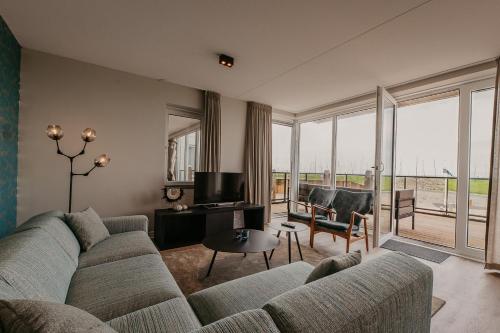 a living room with a couch and a television at Residence Oude Haven luxe appartementen met sauna in Colijnsplaat