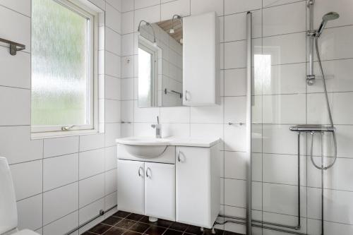 y baño blanco con lavabo y ducha. en Five-Bedroom holiday home by the river of lagan, en Knäred