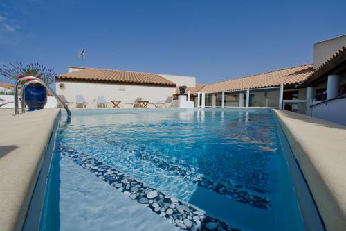 a swimming pool in a villa with blue water at Le Maset en Camargue in Saintes-Maries-de-la-Mer