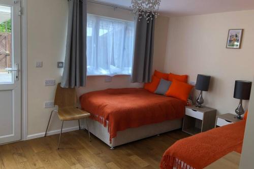 a bedroom with a bed with orange pillows and a window at Guest house in the New Forest near Paulton's Park in Cadnam