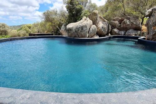 a swimming pool with blue water and rocks at Lettu di Ita - Spectacular Gallura Stazzu with sea view and pool in Santa Teresa Gallura
