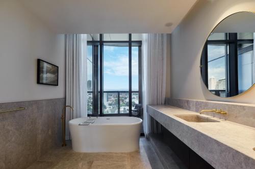 a bathroom with a large tub and a large window at Eos by SkyCity in Adelaide
