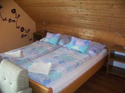 a bed in a room with a wooden wall at Nefelejcs Apartman in Fertőhomok