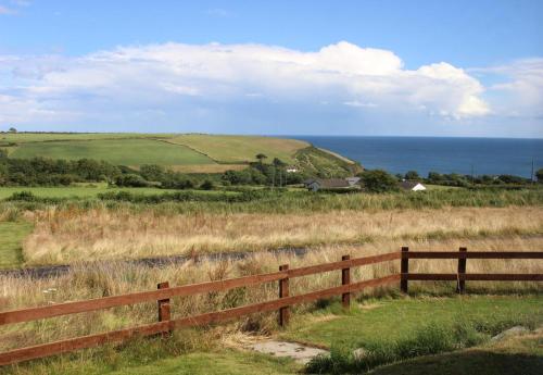 a wooden fence in a field with the ocean at Follies Suites Ballyvoile in Dungarvan