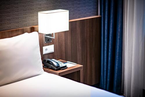 a hotel room with a bed and a phone on a night stand at Holiday Inn Express Amsterdam - Schiphol by IHG in Hoofddorp