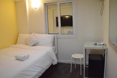 een kleine kamer met een bed, een tafel en een raam bij J mini hotel & house in Seoul