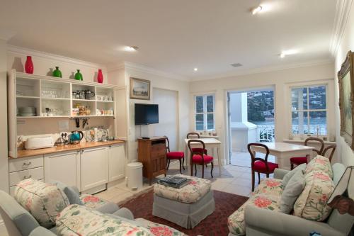 a living room with couches and a table and a kitchen at Isola Bella Guest House in Knysna