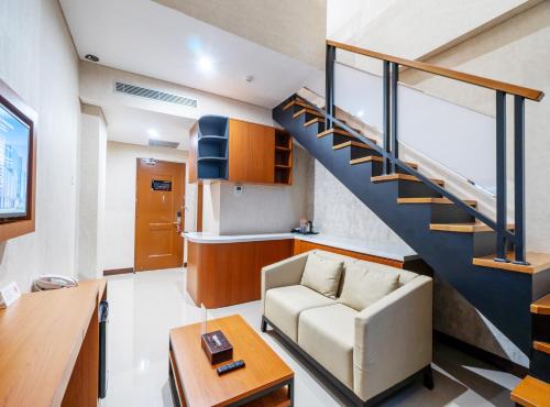 a living room with a staircase and a couch at Braling Grand Hotel Purbalingga, Azana Hotels Collection in Purbolinggo