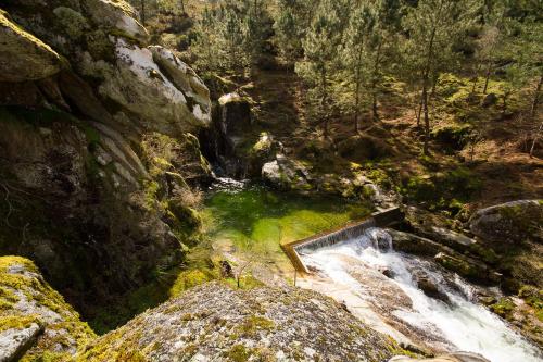a waterfall in the middle of a forest at Casa do Charco Peneda Gerês in Parada