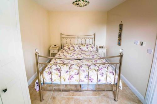 a bedroom with a bed with a floral bedspread at Bwthyn Bach Cozy country retreat in Criccieth