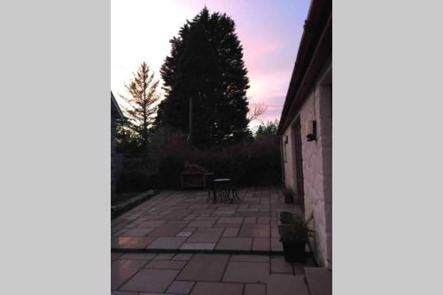 a view of a patio with a table and trees at Bwthyn Bach Cozy country retreat in Criccieth