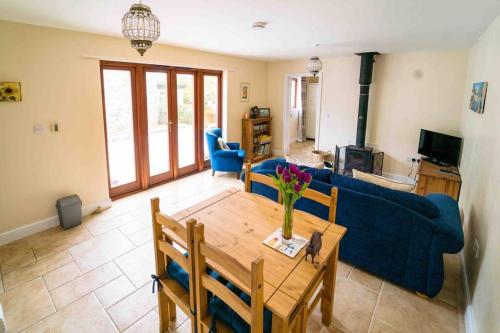 a living room with a table and a blue couch at Bwthyn Bach Cozy country retreat in Criccieth