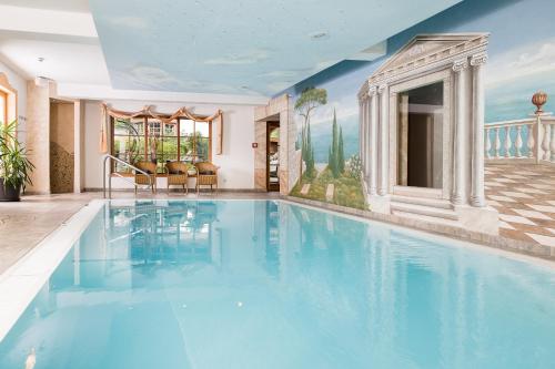 a swimming pool in a house with a painting on the wall at Hotel Langeck in Maria Alm am Steinernen Meer